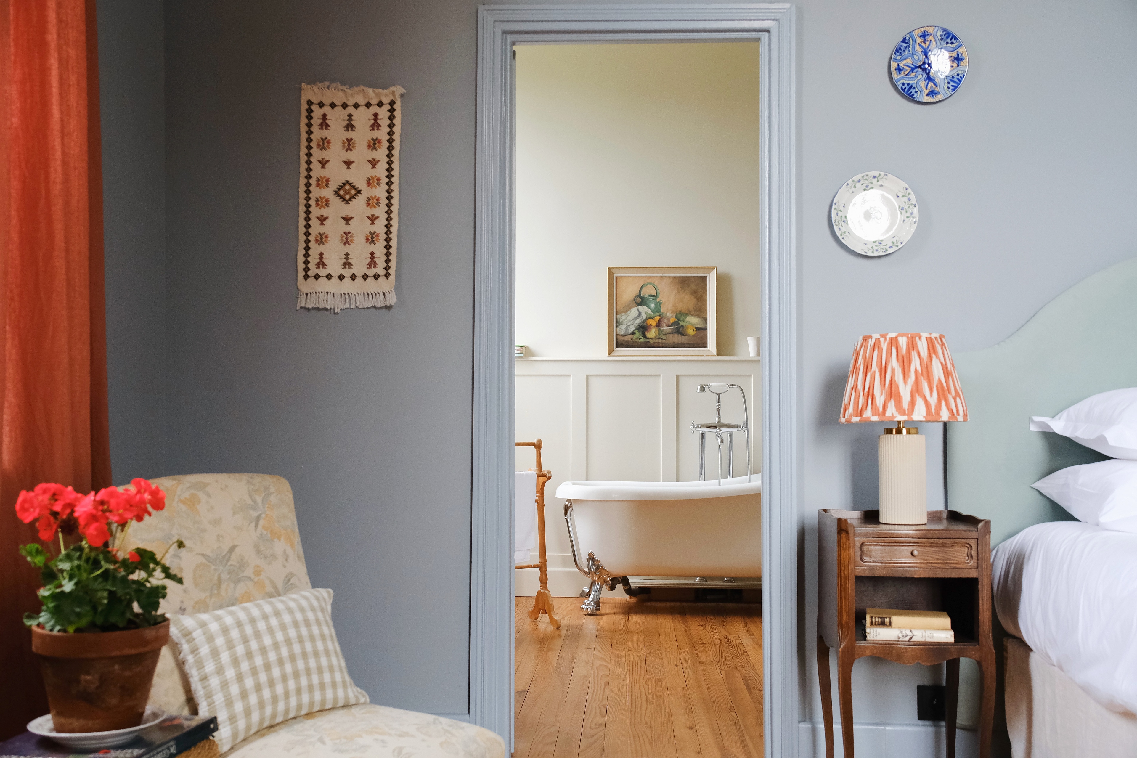 Pale blue bedroom at the Château at Pomiro, looking through to a roll top bath