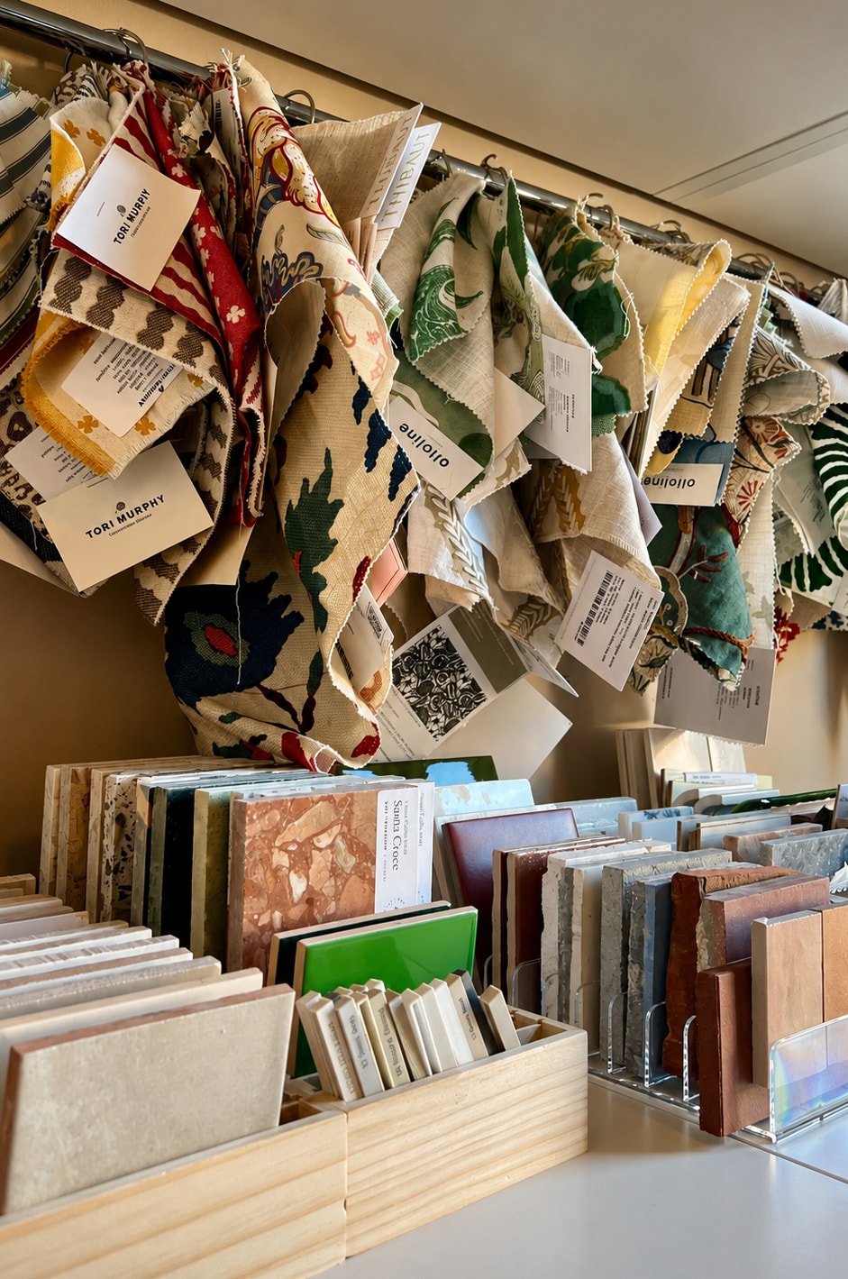 Fabric samples hanging on a rail above trays of tile and stone