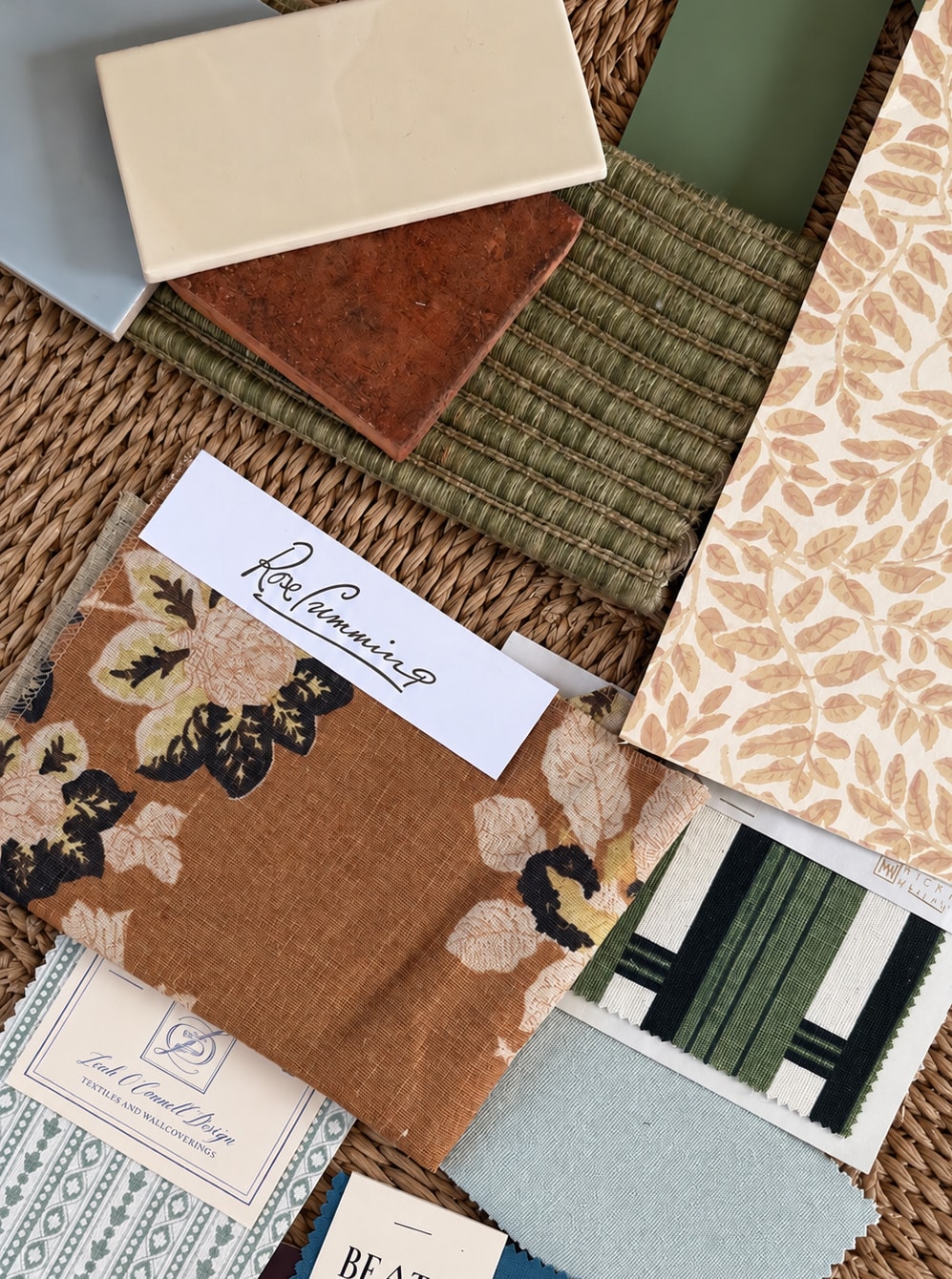 Fabric, wallpaper and tile samples laid out on a seagrass mat